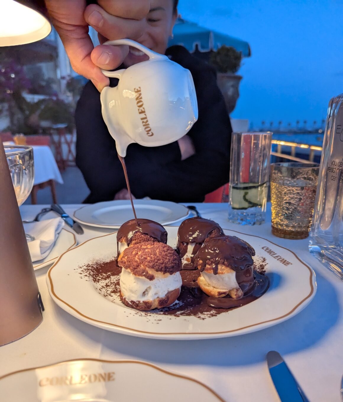 waiter pouring out the cocoa sauce onto the craquelin choux pastry filled with ice cream at Corleone in Cascais